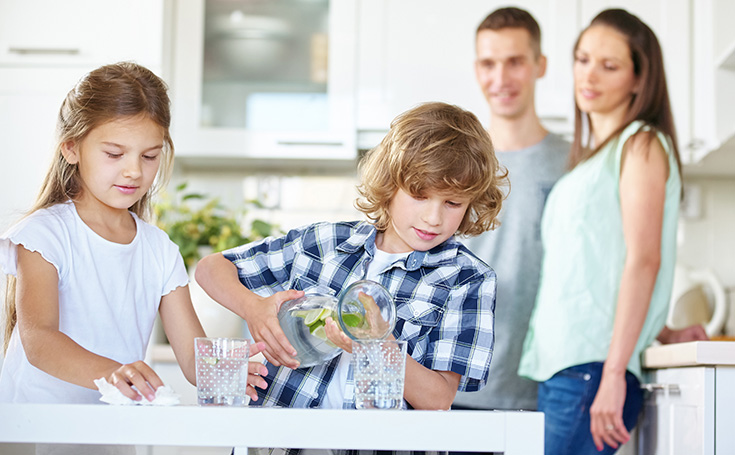 Familie gießt Wasser in Gläser ein